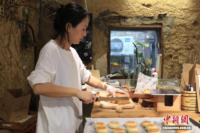 中国侨网10月14日，一家乡村柴窑面包店中，店主将现烤面包切块。近年来，浙江杭州周边乡村陆续涌现多家柴窑面包店，不仅丰富了消费者的选择，也为乡村带来更多游客。吴怡欣 摄